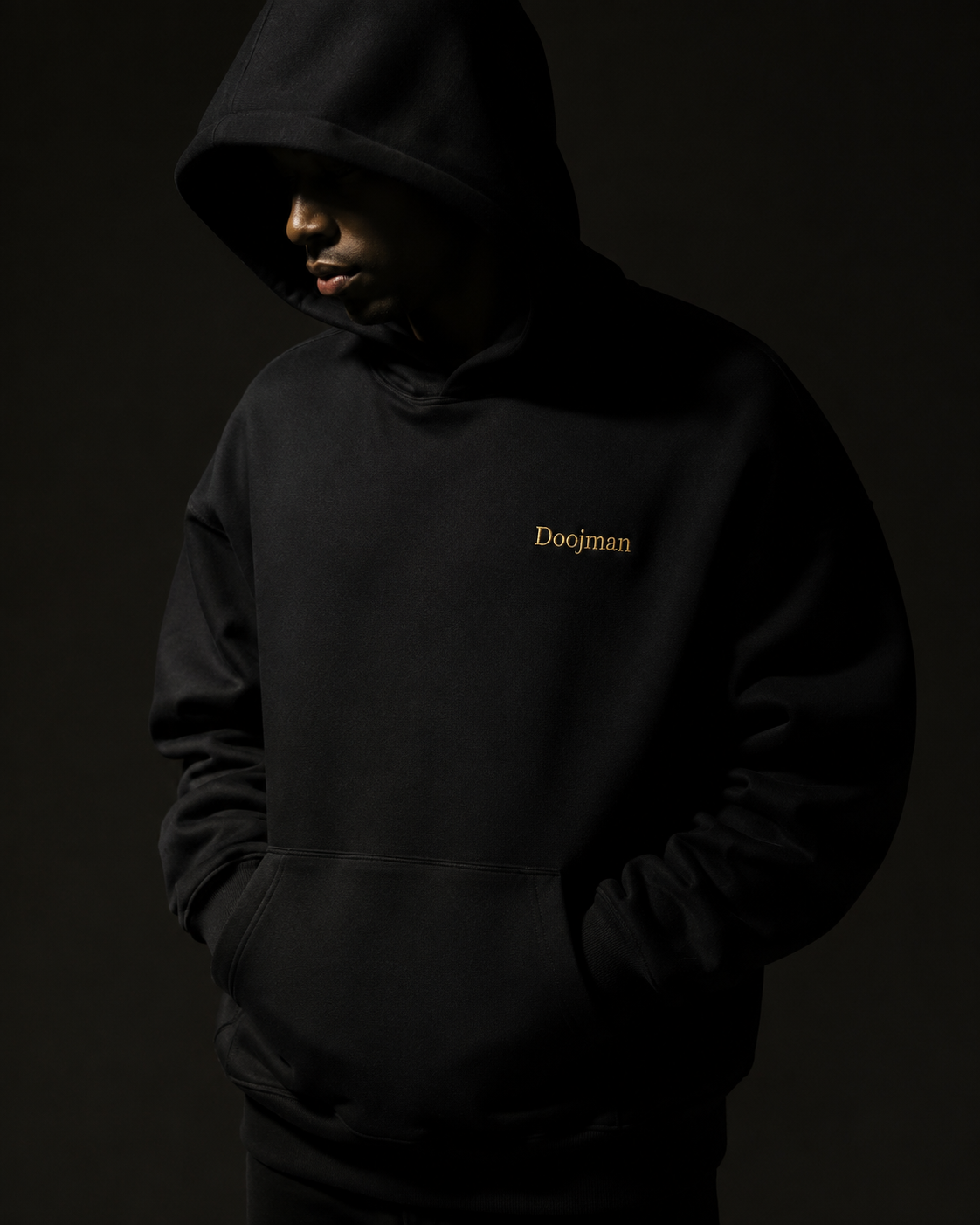 Black Doojman hoodie with gold embroidery, campaign concept in warm studio light